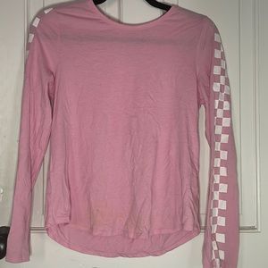 A long sleeve pink shirt that has white checkers down the sleeves